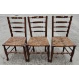 A set of three 19th Century rush seat ladder back standard chairs
