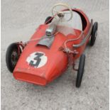 A child's Tri-ang metal pedal operated racing car, painted red, and a child's scooter