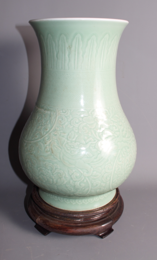 A K'ang Hsi incised celadon glazed vase, 12 1/2" high, on carved hardwood stand