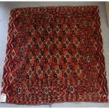 A Bokhara rug decorated twenty-four rectangular panels on a red ground with numerous border stripes,
