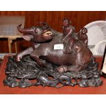 A 19th Century Chinese carved hardwood figure of a buffalo with two figures on its back, on hardwood