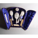 A silver dressing table set with embossed decoration, in fitted travel case