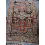 A Caucasian rug decorated three cruciform medallions on a red and black ground with three border