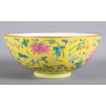 A Chinese porcelain bowl decorated scrolled floral motifs on a yellow ground, gilt rim, four