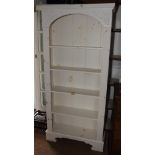A pair of white painted open bookcases with arched tops and reeded pilasters, fitted five shelves,