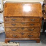 An early 18th Century walnut bureau with sloping flap and inlaid herringbone stringing and four