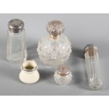 A cut glass scent bomb with embossed silver lid, three silver mounted dressing table jars, a
