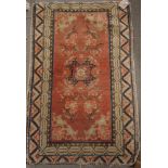 A Persian rug decorated stylised flowers and central medallion on a red ground with two border