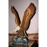 A bisque porcelain sculpture of a bald eagle over water with talons extended, 29" high