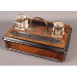 A Victorian walnut and ebonised desk inkstand, fitted two square glass inkwells, a papier-mache