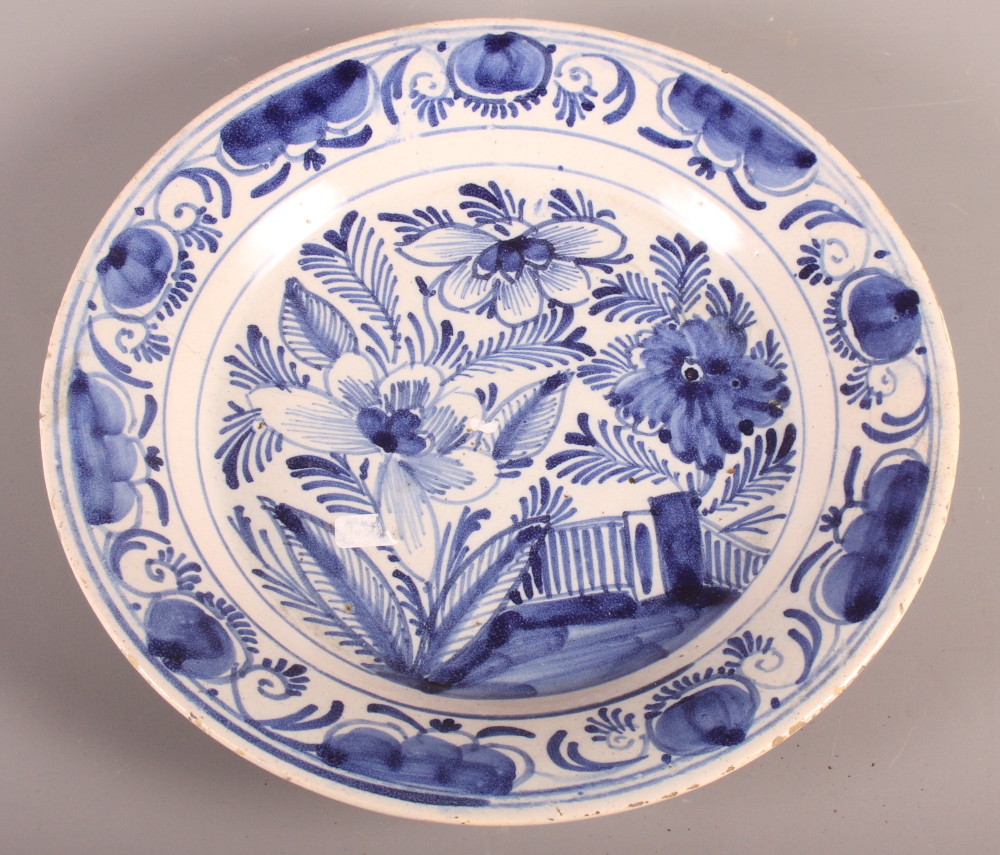 An 18th Century blue and white Delft plate with tree and fence decoration, 9" dia (hair crack)