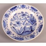 An 18th Century blue and white Delft plate with tree and fence decoration, 9" dia (hair crack)