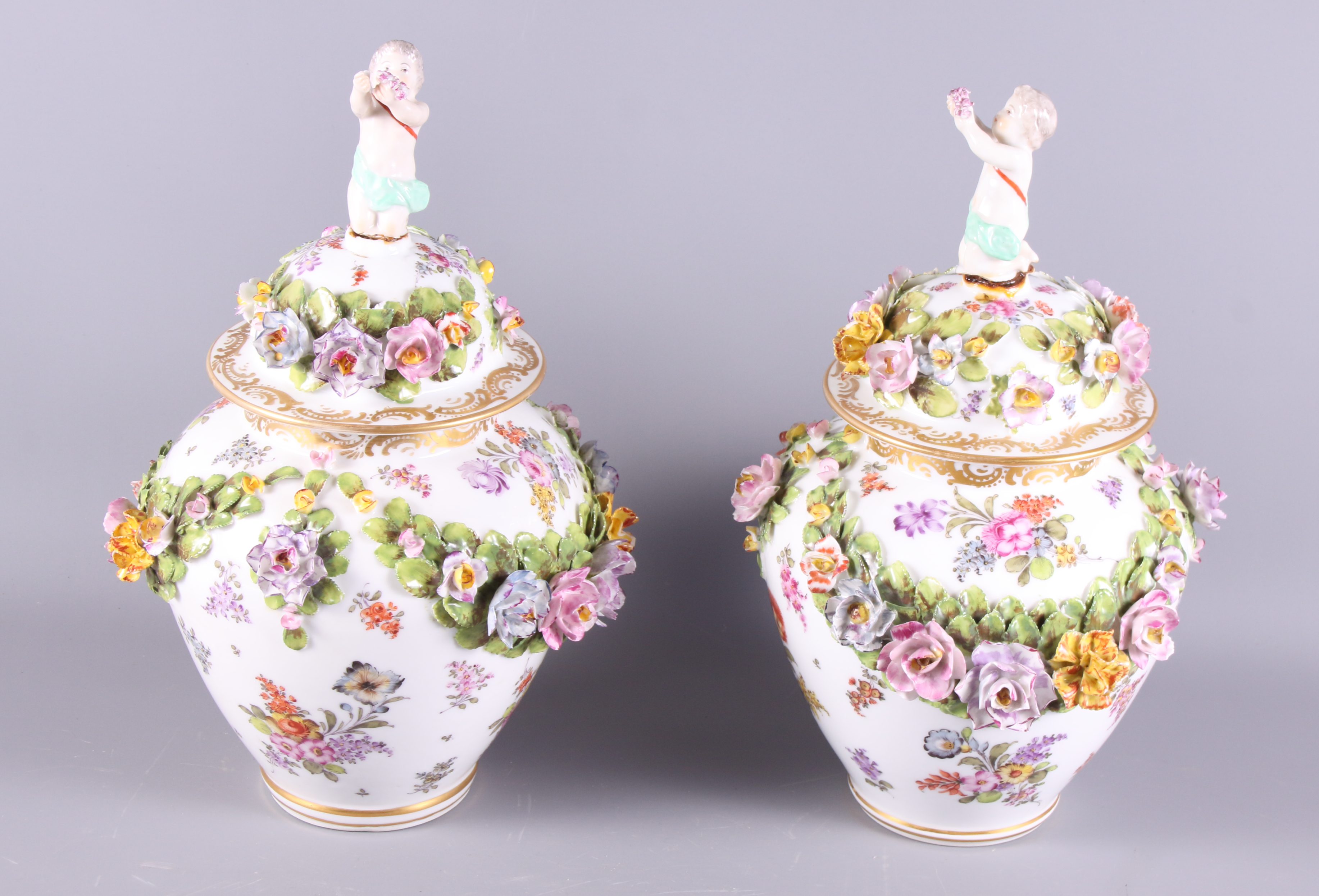 A pair of 20th Century Dresden oviform jars and covers with relief decoration of flowers and putto