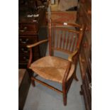 An Arts & Crafts spindle back elbow chair with rush envelope seat