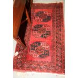 A Bokhara rug decorated three octagonal guls on a red ground, 57" x 32" approx, and a smaller rug,