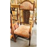An early 20th century high backed oak armchair with padded head rest and seat upholstered in a
