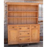 A waxed pine kitchen dresser with boarded back fitted two shelves, over base fitted five drawers and