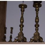 A pair of Continental brass scrollwork and angel decorated pricket candlesticks, on triform bases,