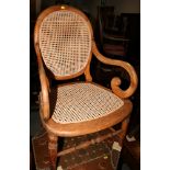 A Victorian open armchair with oval cane back and seat, scroll shaped arms and another dark