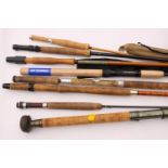 A collection of assorted fly fishing rods, some with bags