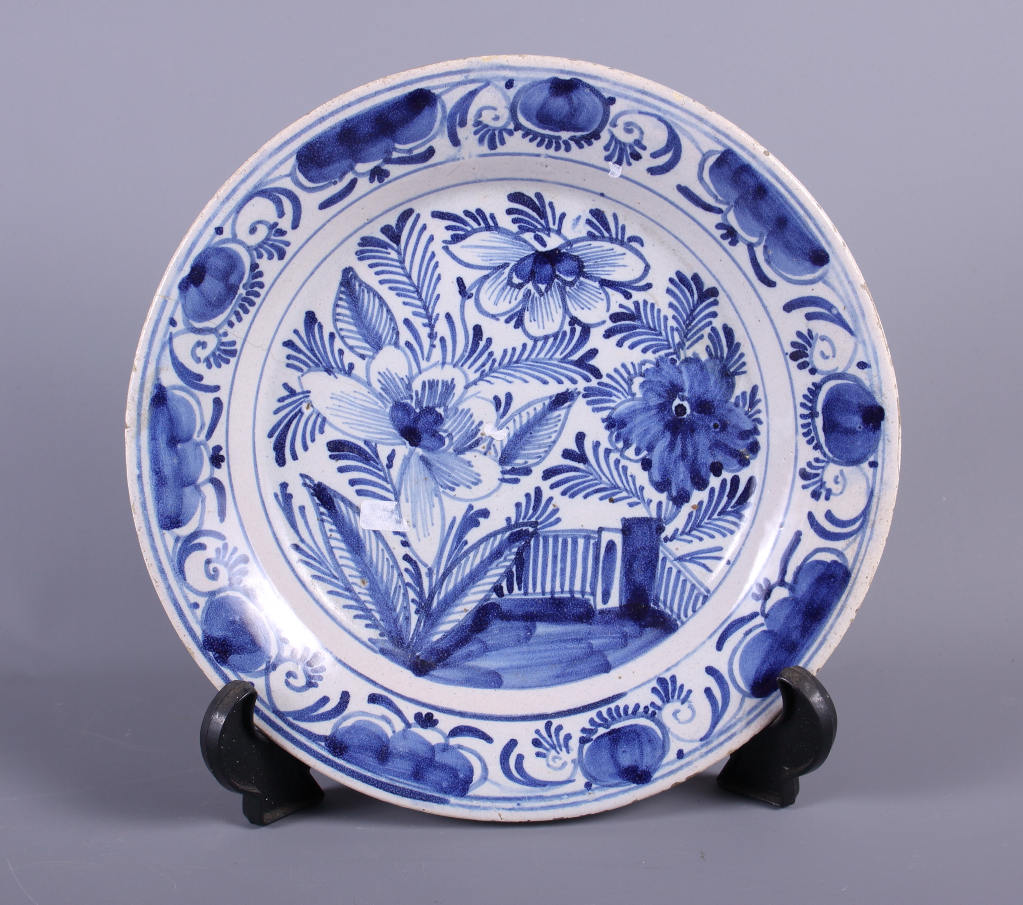 An 18th century blue and white Delft plate with tree and fence decoration, 9" dia (hair crack)