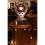 A late 18th century mahogany hall chair with circular back, decorated central panel painted