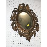 An oval wall mirror, in cast gilt metal frame with eagle surmount, 15" x 11" overall