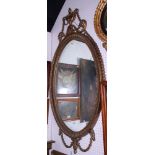 An early 20th century oval gilt framed wall mirror with giltwood surmount, carved urn and scrolls,