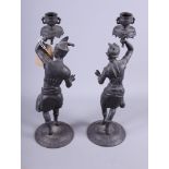 A pair of cast black metal candlesticks of dancers in African? dress, 15" high