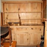 A waxed pine kitchen dresser with boarded back, fitted two shelves, over base fitted three drawers