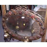 An oval bevelled wall mirror, in gilt and floral decorated barbola frame with ribbon surmount, 31" x