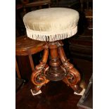 A Victorian walnut piano stool with revolving adjustable seat, on three scroll carved supports