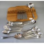 A Japanese stainless steel suite of cutlery, on wooden board