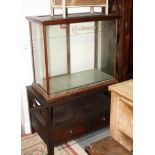 A stained wooden framed display cabinet, fitted two glass shelves enclosed by sliding glass doors,