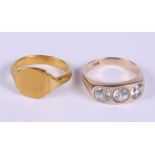 A yellow metal signet ring (tests as high grade gold), 12.2g, and a yellow metal three stone ring,