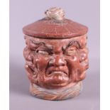A mid 19th century painted terracotta tobacco jar with demon faces, 6" high