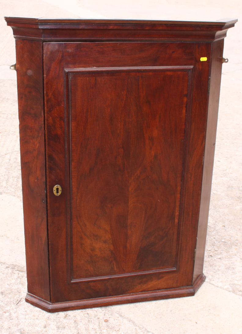 An early 19th century mahogany wall hung corner cabinet enclosed plain panelled door