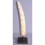 An African ivory tusk, carved spiralling band of figures, on wooden base, 16" high