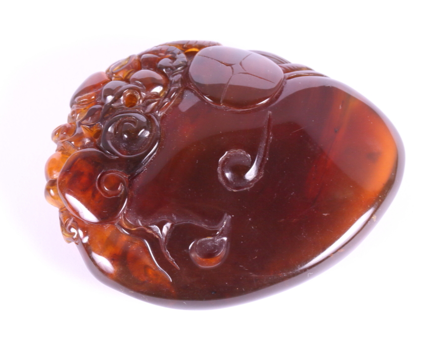 A Chinese carved amber pebble decorated dragon