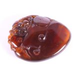 A Chinese carved amber pebble decorated dragon