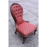 A Victorian carved walnut showframe spoon back armchair, button upholstered in a red fabric, on