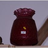 A dimpled ruby glass oil lamp shade and a number of other coloured glass shades