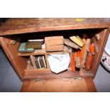 A wooden cabinet with brass carrying handle and drop down door containing assorted fishing