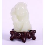 A Chinese carved pale green celadon jade figure, on carved hardwood stand, 3" high overall