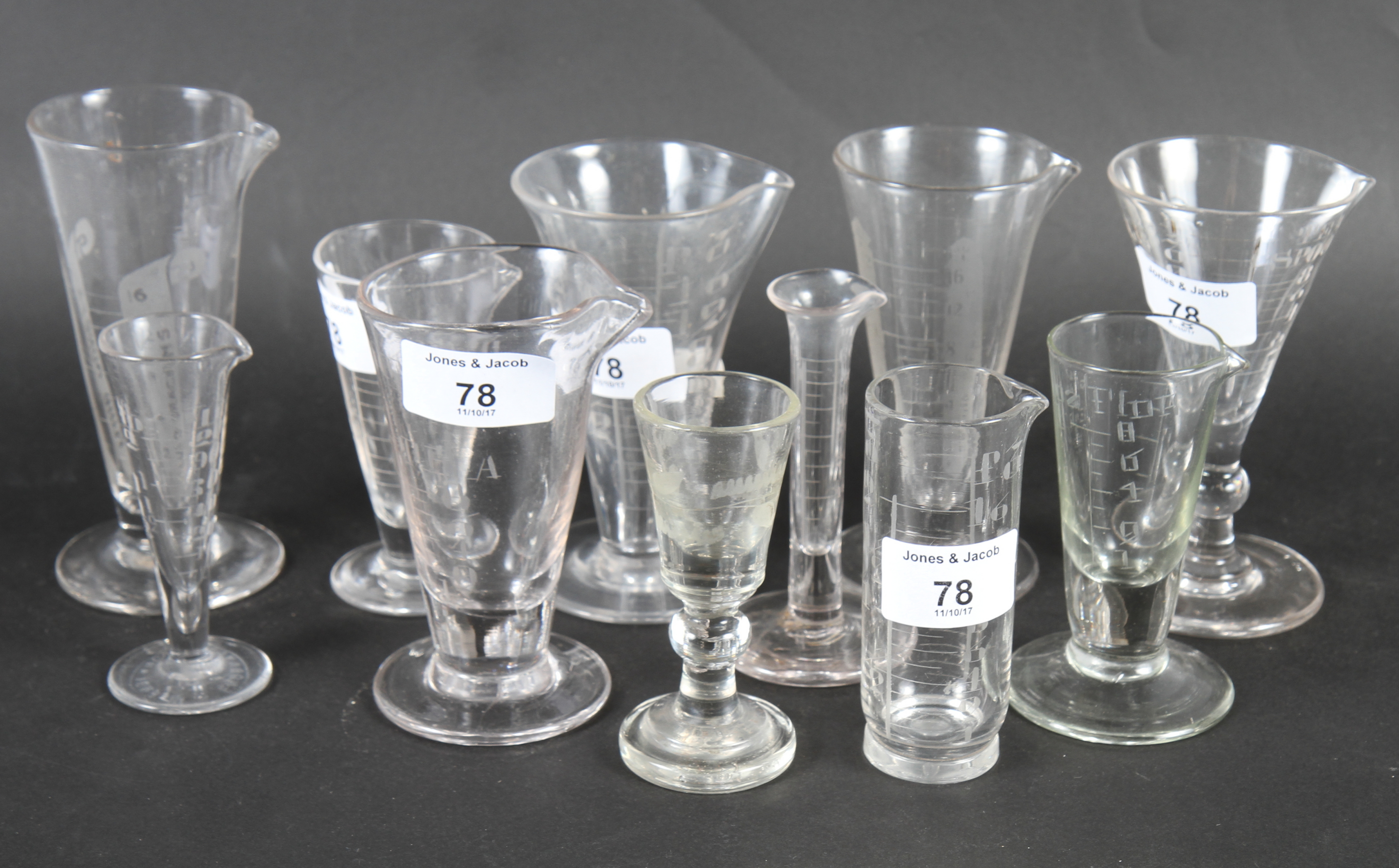 A collection of assorted conical glass medicine measuring glasses
