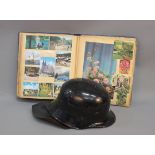 A German black tin hat with neck cover and a 20th century scrap book containing poetry cuttings,