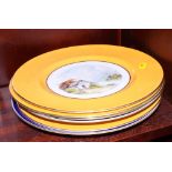 Three Crown Derby wall plates with yellow borders, centres painted landscapes by W E J Dean, an