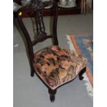 A late Victorian dark stained salon nursing chair with carved and pierced central splat and