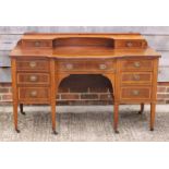 An Edwardian mahogany and satinwood banded sideboard with bowed central section, fitted nine