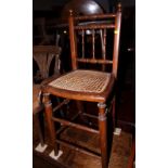 A child's deportment chair with cane seat and spindle turned back and a Victorian dark stained